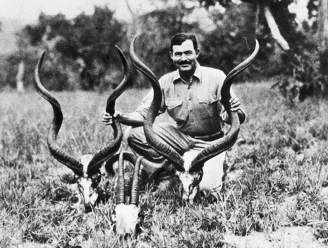 1937:  American writer Ernest Hemingway (1899 - 1961) kneels while holding a pair of antelope horns during a safari, Africa.  (Photo by Hulton Archive/Getty Images)